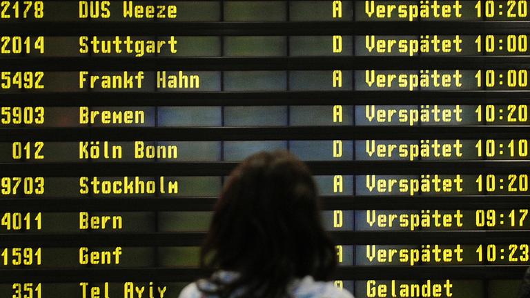 Archiv: Eine Frau steht am 10.12.2010 auf dem Flughafen Berlin-Schönefeld vor einer Anzeigetafel