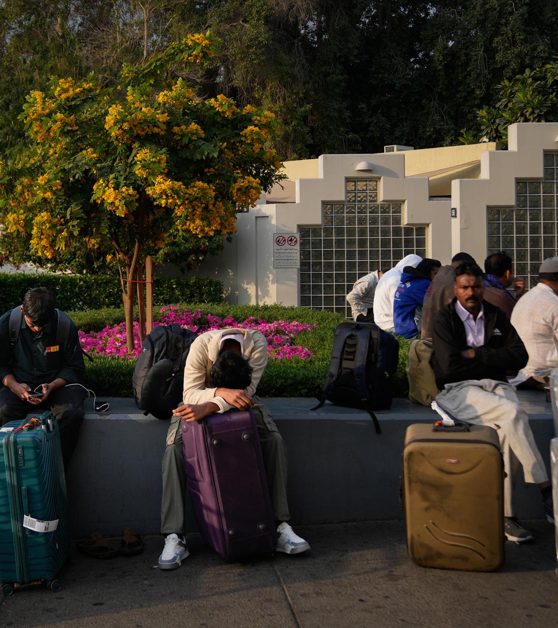 Passagiere, die durch die Schließung des internationalen Flughafens von Dubai gestrandet sind, warten auf dem Flughafenparkplatz in Dubai. 