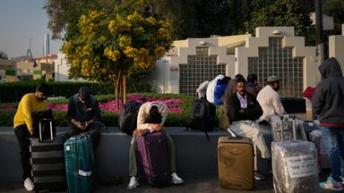 Passagiere, die durch die Schließung des internationalen Flughafens von Dubai gestrandet sind, warten auf dem Flughafenparkplatz in Dubai. 