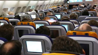 In einem Flugzeug sitzen Fluggäste auf ihren Plätzen.