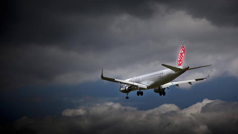 Maschine der Fluggesellschaft Niki fliegt unter dunklen Wolken 