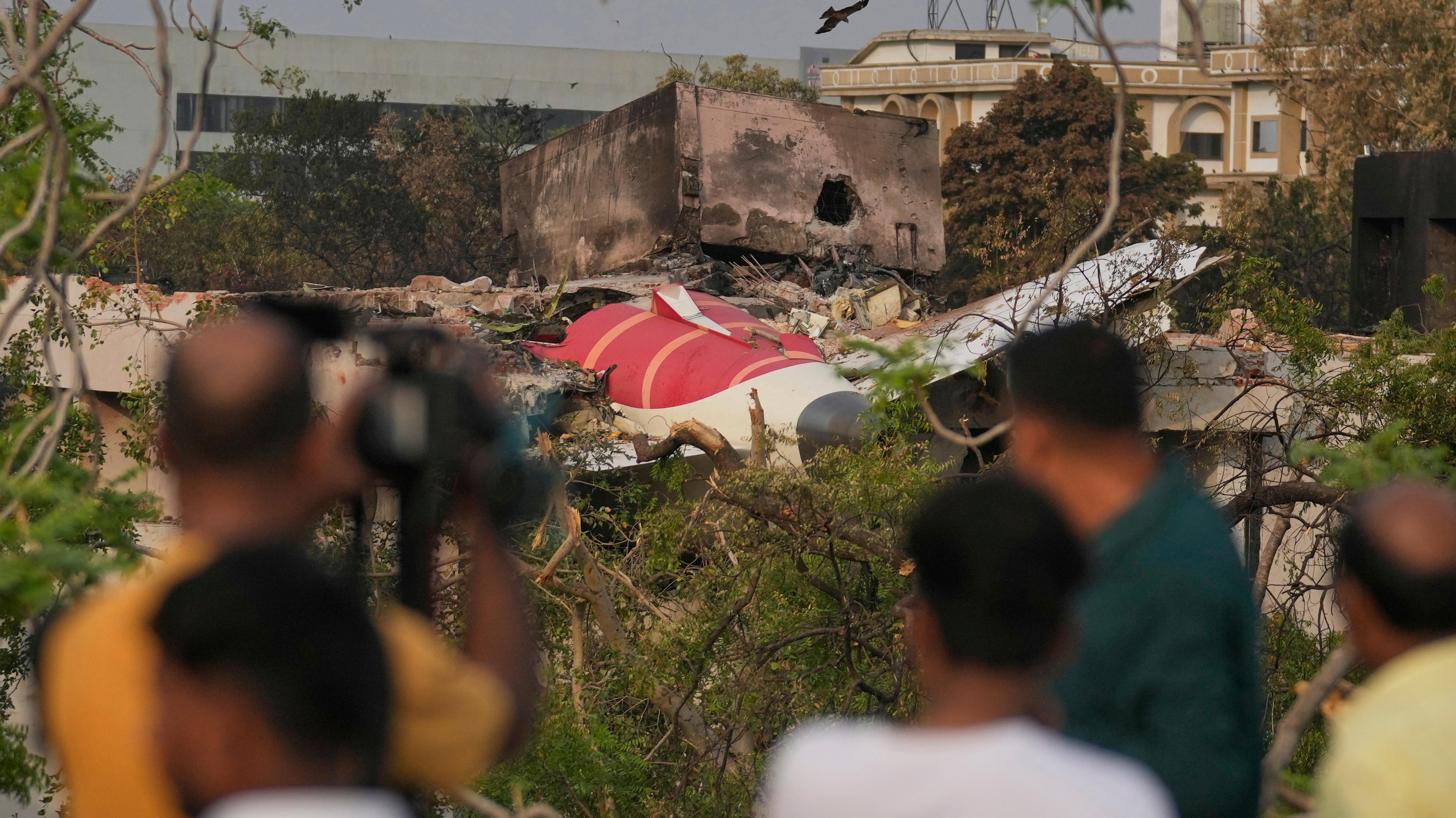 Indien, Ahmedabad: Menschen betrachten die Wrackteile des am Donnerstag (12.06.2025) abgestürzten Flugzeugs von Air India.
