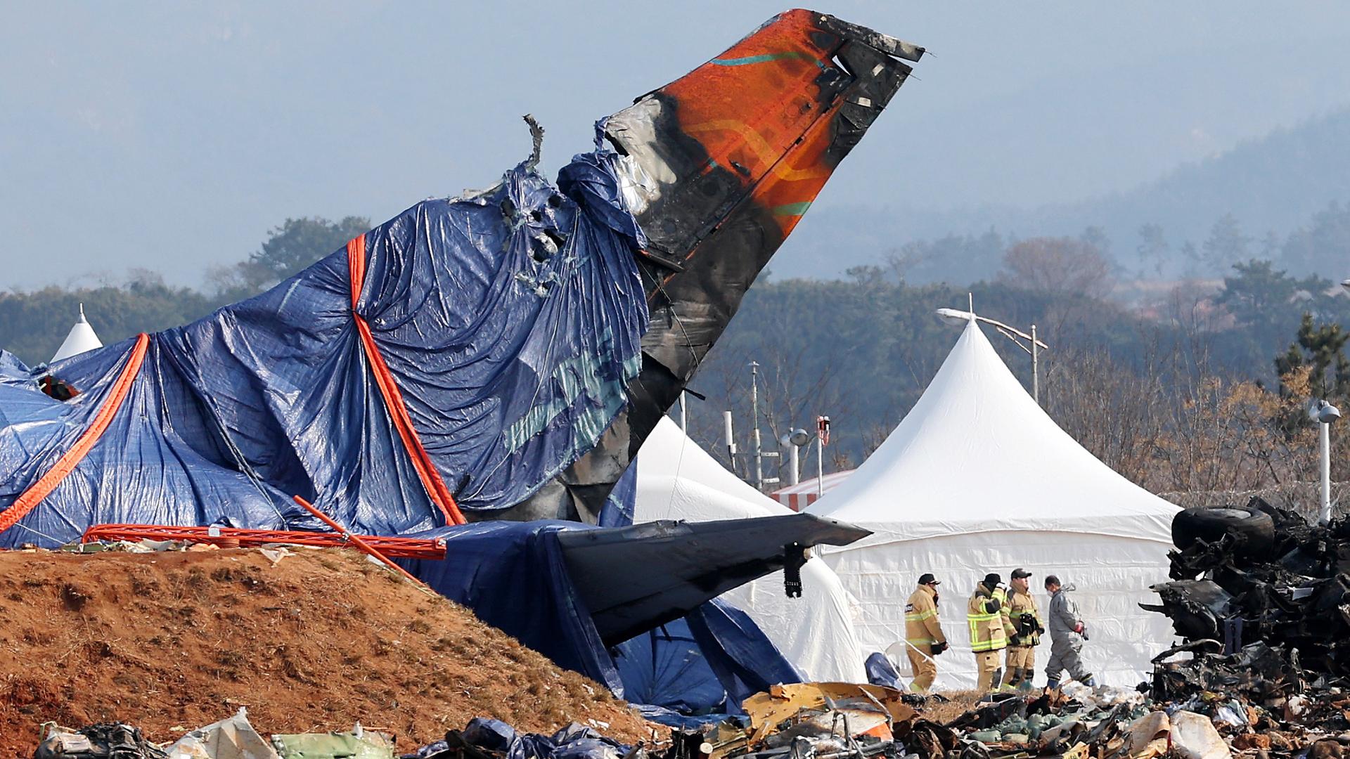 Feuerwehrleute untersuchen die Absturzstelle des Flugzeugs Jeju Air am internationalen Flughafen Muan im Landkreis Muan, Südkorea