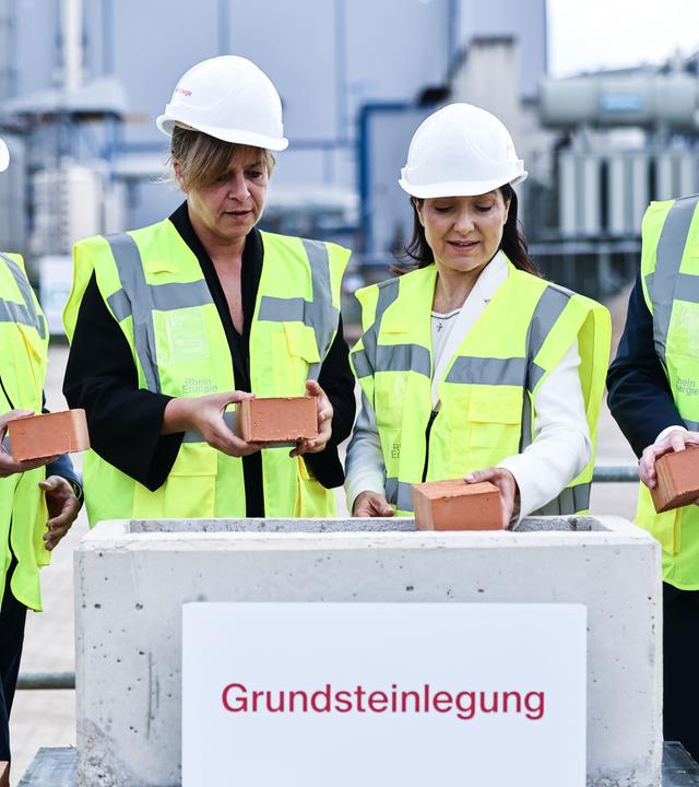 Bundeswirtschaftsministerin Katherina Reiche (CDU), Kölns Oberbürgermeister Torsten Burmester (SPD), NRW-Wirtschaftsministerin Mona Neubauer (Grüne) und RheinEnergie-Vorstand Andreas Feicht verschließen den Grundstein für eine Flusswasser-Wärmepumpe.
