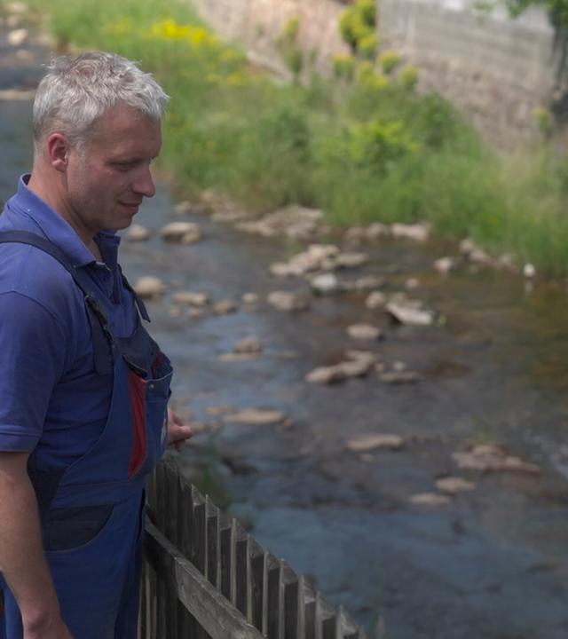 Maik Friebel steht am Zaun seines Grundstücks in Schmiedeberg und blickt auf das kleine Flüssche "Rote Weißeritz"