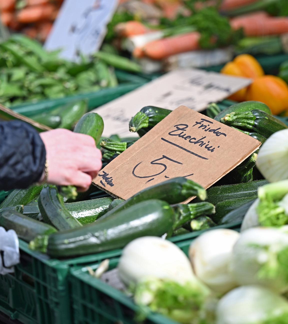  Eine Frau greift an einem Marktstand nach einer Zucchini, die mit «5 Euro/kg» ausgezeichnet ist. 