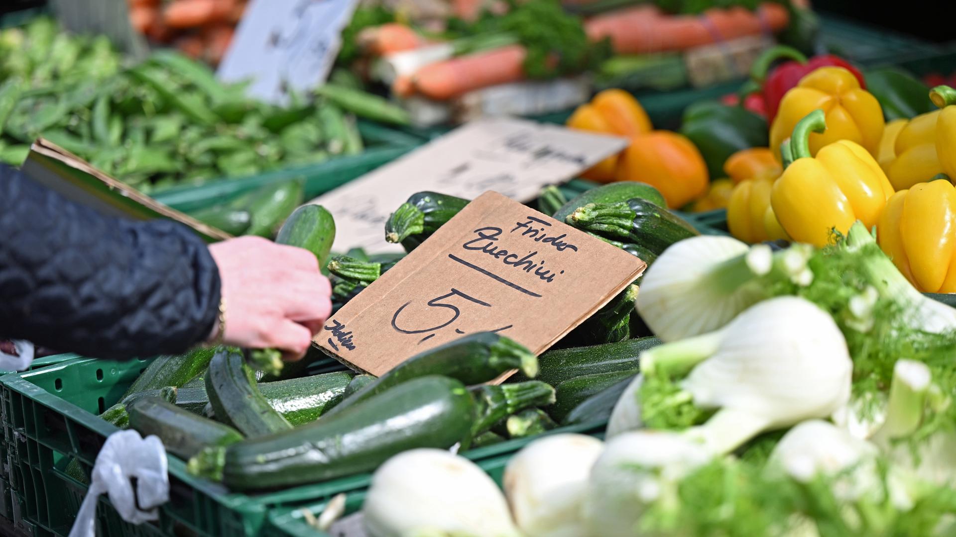  Eine Frau greift an einem Marktstand nach einer Zucchini, die mit «5 Euro/kg» ausgezeichnet ist. 