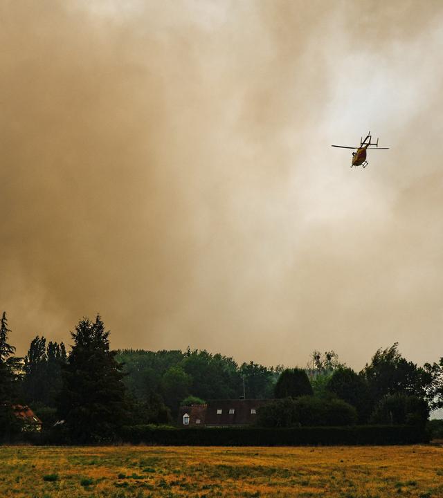 Rauch steigt in den Himmel auf, während Waldbrände durch den historischen Wald von Fontainebleau wüten. Ein Hubschrauber fliegt über den Wald