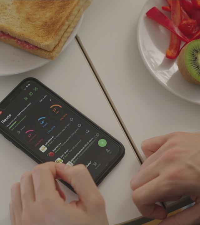 Handy mit geöffnter App liegt auf gedecktem Frühstückstisch