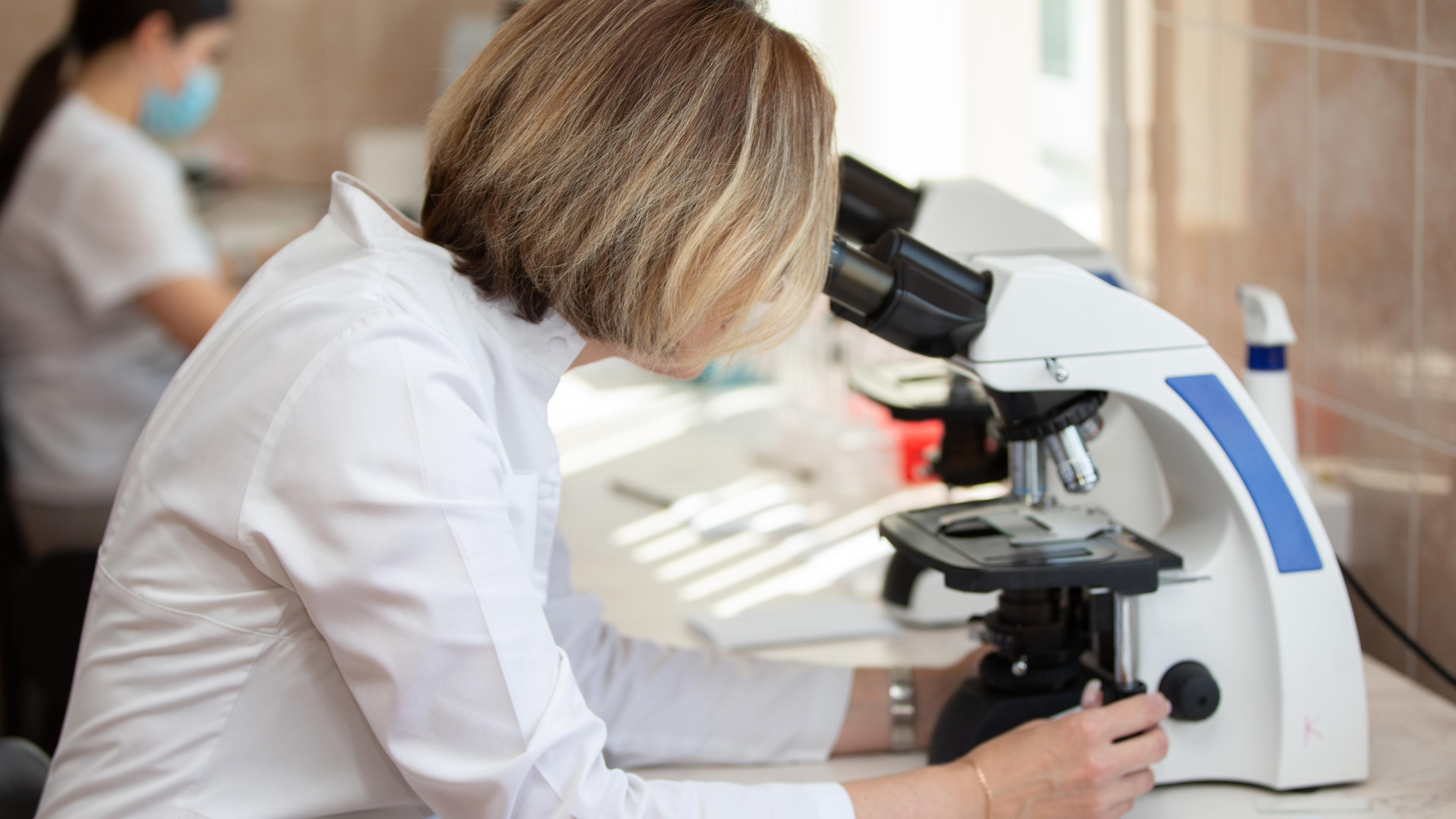 Wissenschaftlerin an einem Mikroskop