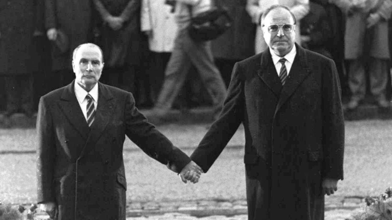 Francois Mitterrand und Helmut Kohl, wie sie während einer deutsch-französischen versöhnungszeremonie vor dem Friedhof von Doaumont händchenhaltend ihre jeweiligen Nationalhymnen hören.