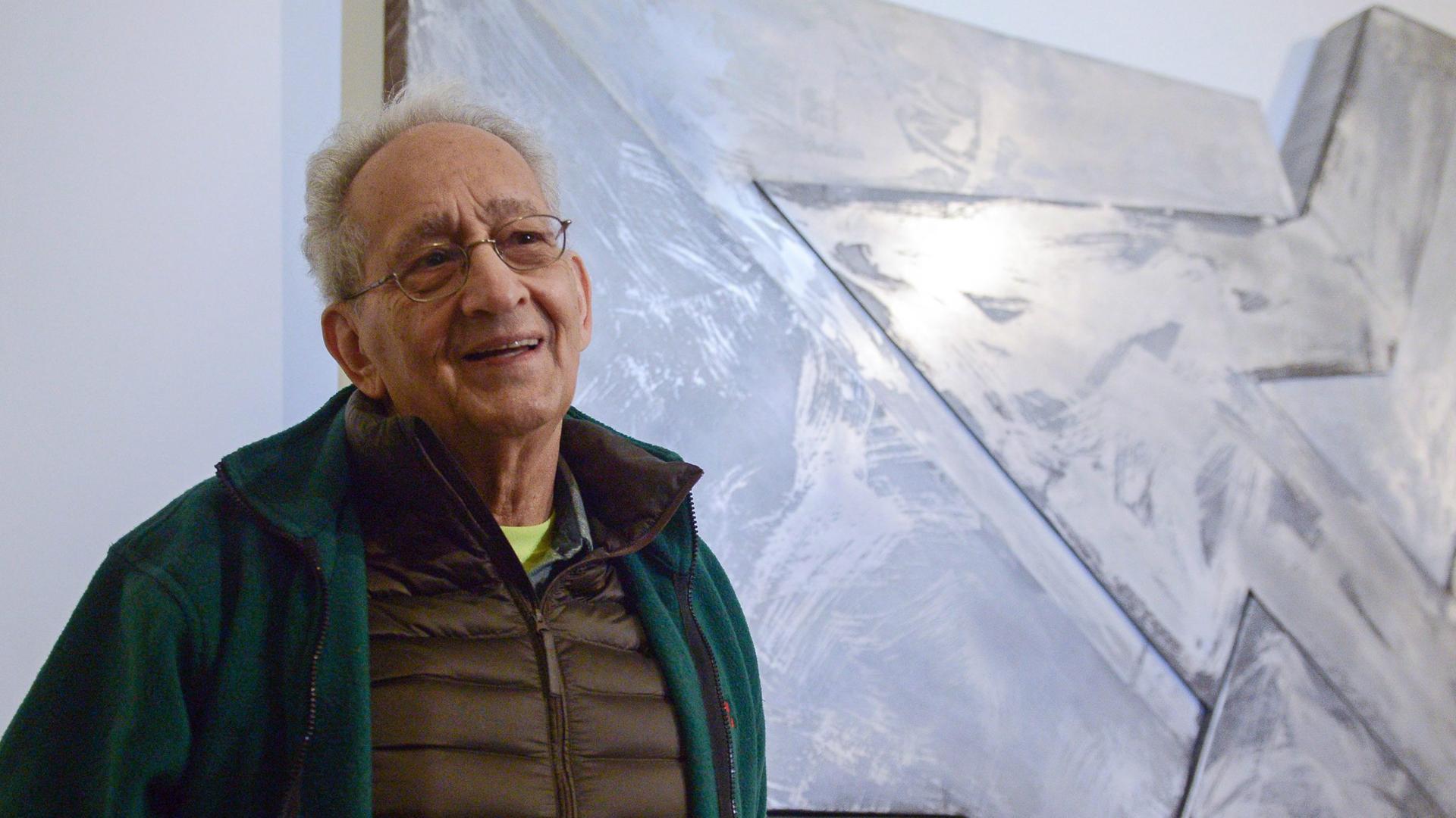 Frank Stella posiert vor einem seiner Werke in einer Ausstellung in Warschau.