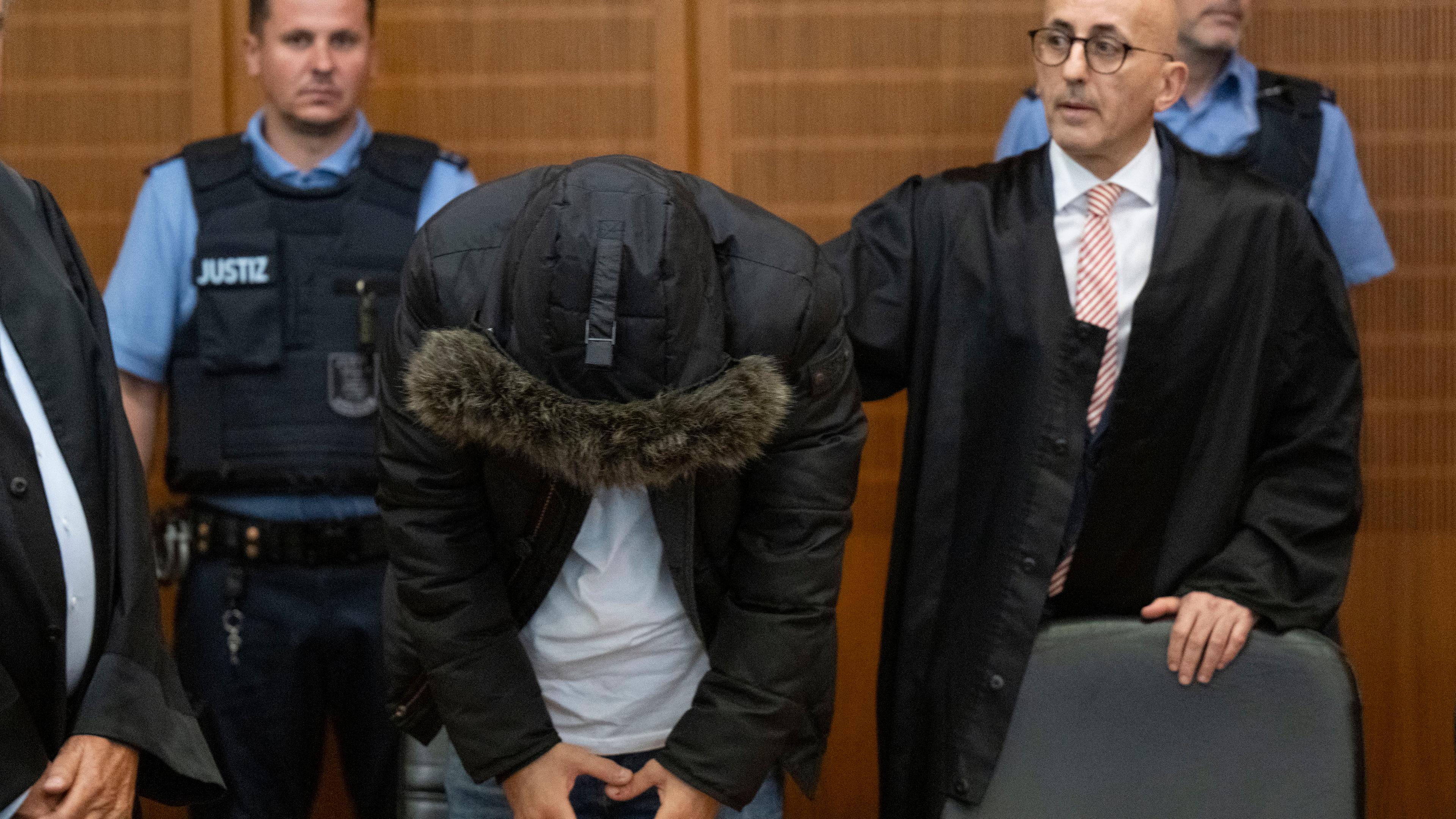 Der angeklagte, syrische Arzt (2.v.l.) steht vor der Urteilsverkündung neben seinem Anwalt Oussama Al-Agi (2.v.r.) im Oberlandesgericht.