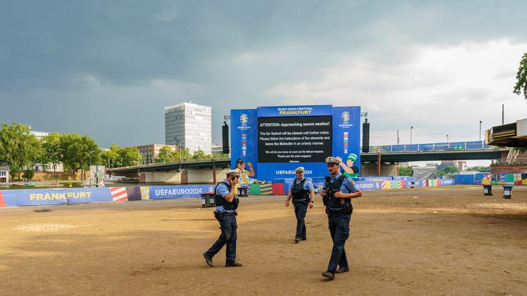 Polizisten kontrollieren die Räumung der Frankfurter Fanzone. Sie wurde aufgrund einer Unwetterwarnung geräumt.
