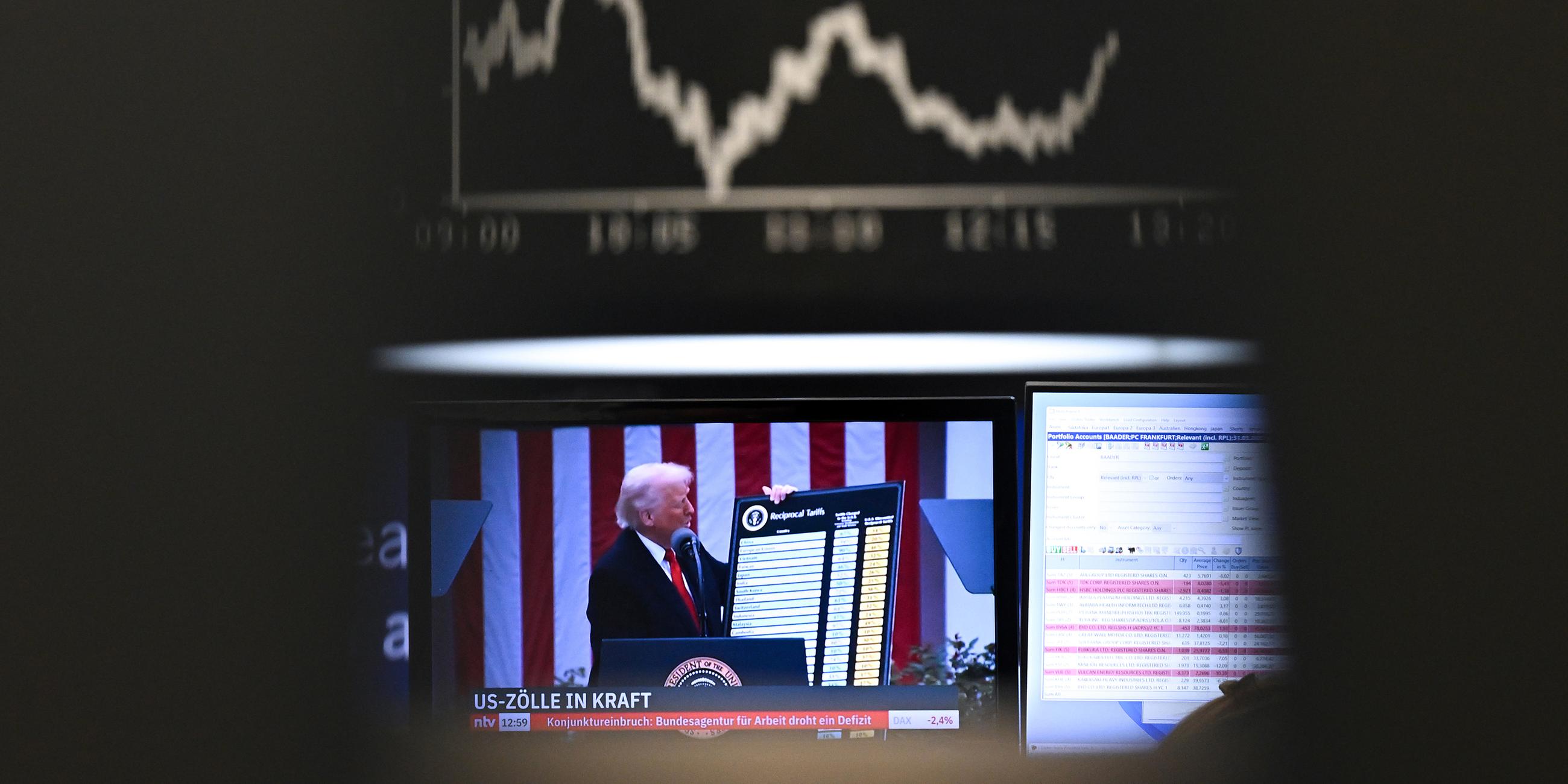 US-Präsident Trump ist auf einem Bildschirm auf dem Parkett der Frankfurter Wertpapierbörse vor der Anzeigetafel mit der Dax-Kurve zu sehen