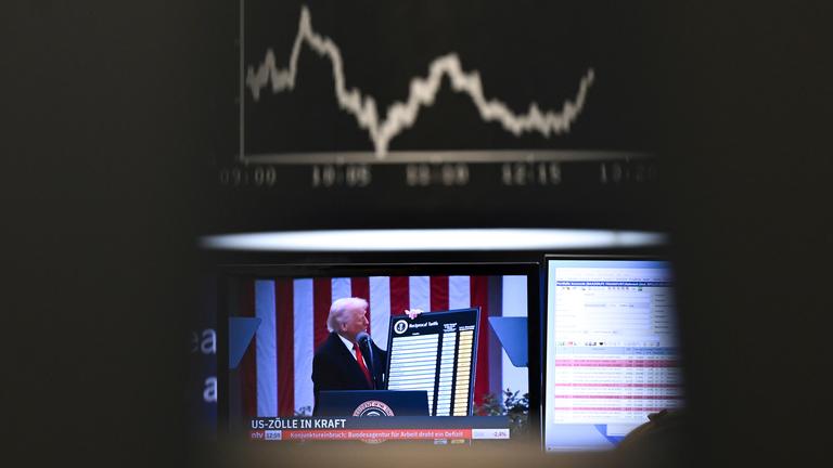 US-Präsident Trump ist auf einem Bildschirm auf dem Parkett der Frankfurter Wertpapierbörse vor der Anzeigetafel mit der Dax-Kurve zu sehen