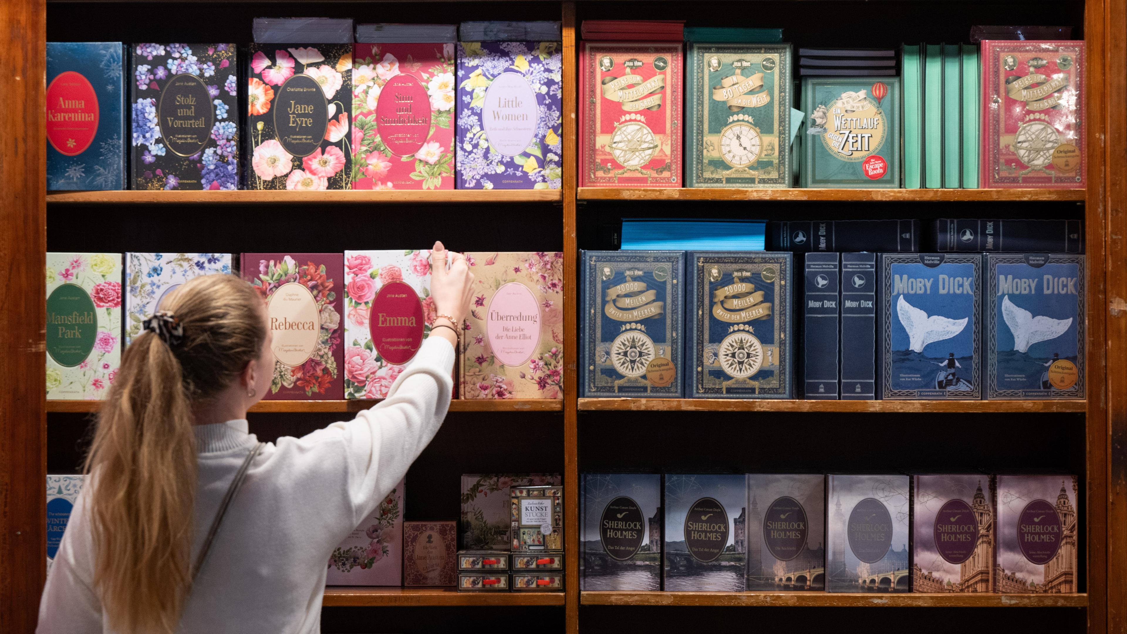 Hessen, Frankfurt/Main: Eine Frau nimmt ein Buch aus einem Regal am Messsestand des Verlags Coppenrath.