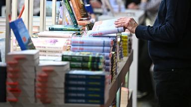 Ein Mann schaut sich beim Kiepenheuer & Witsch Verlag ein Buch an.