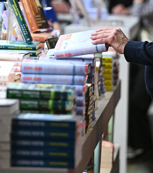 Ein Mann schaut sich beim Kiepenheuer & Witsch Verlag ein Buch an.