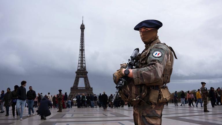 Ein Soldat steht auf dem Trocadero vor dem Eiffelturm in Paris.