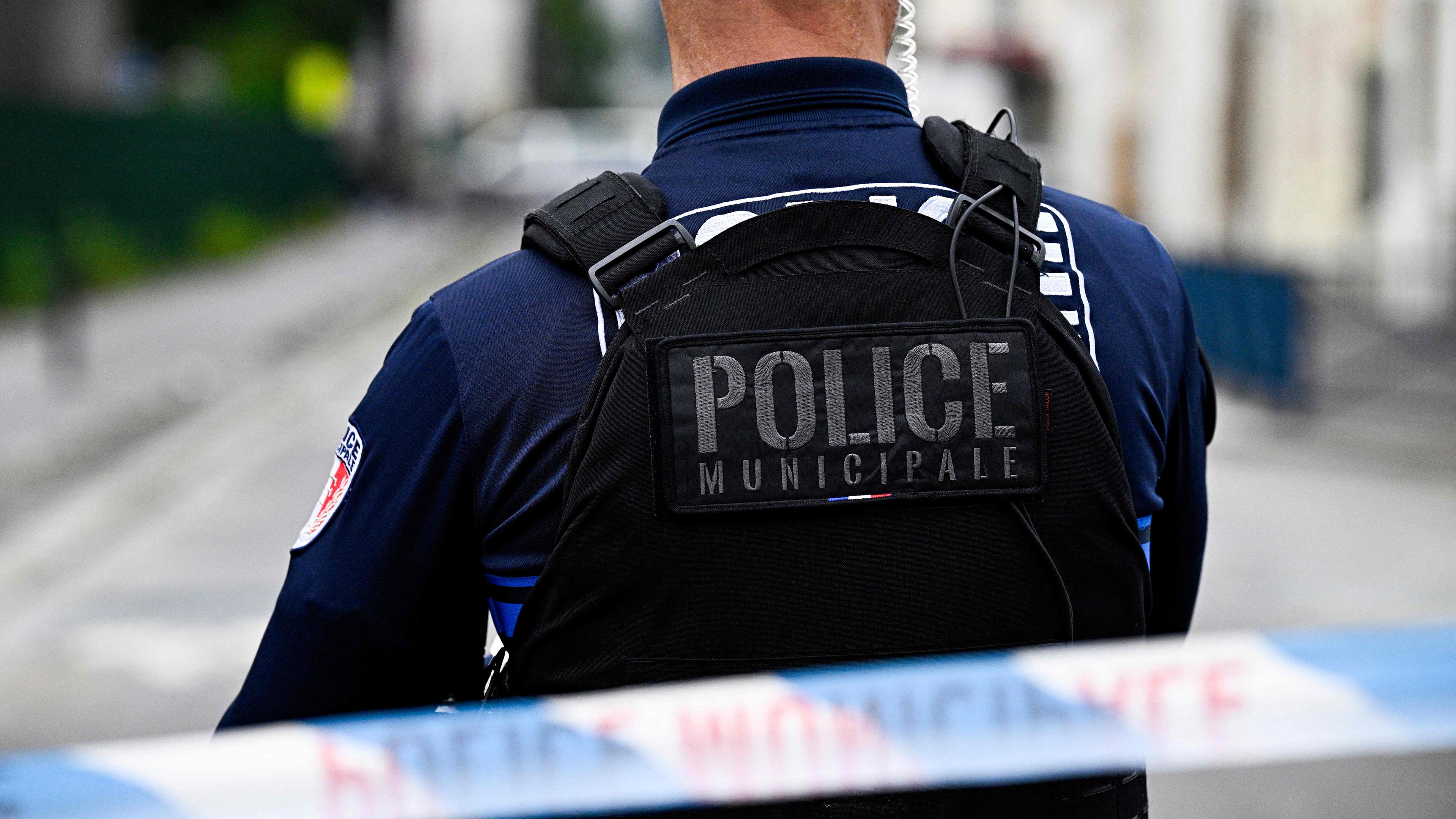 Ein französischer Polizist steht hinter einer Straßenabsperrung.