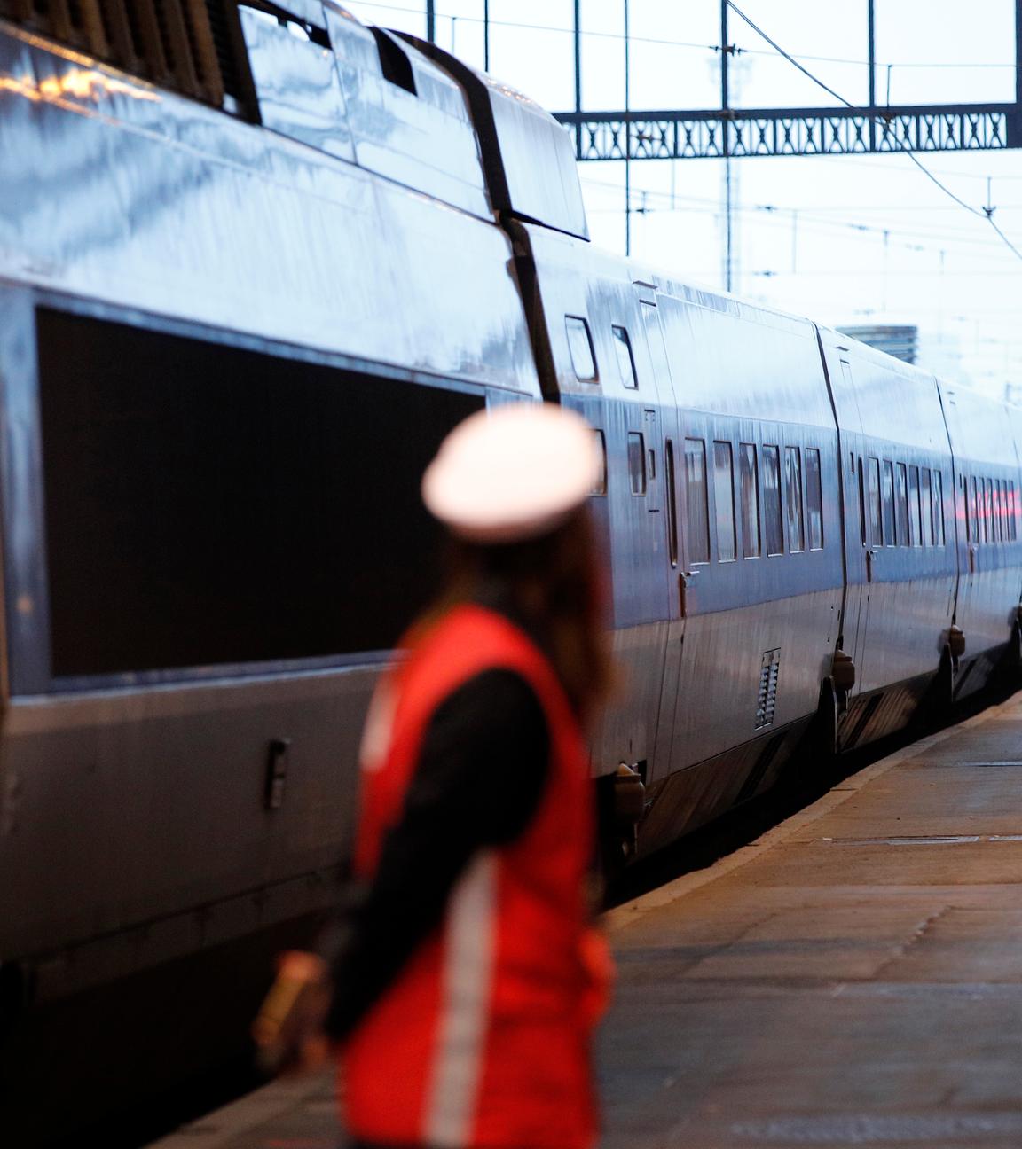 Eine Mitarbeiterin der Bahn steht am Pariser Gare de Lyon auf einem Bahnsteig neben einem TGV. 