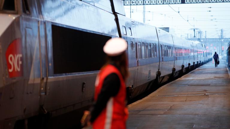 Eine Mitarbeiterin der Bahn steht am Pariser Gare de Lyon auf einem Bahnsteig neben einem TGV. 