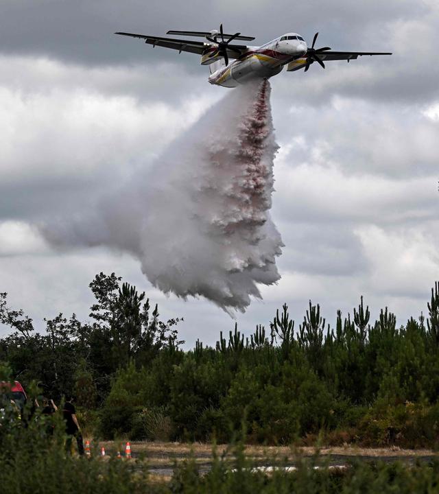 Ein Löschflugzeug vom Typ Dash Q400-MR des Zivilschutzes wirft ein mit Wasser vermischtes Brandhemmungsmittel ab