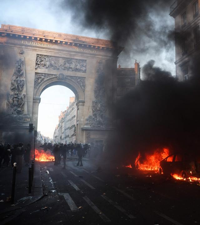 Demonstranten neben einem brennenden Auto in der Nähe der Porte Saint-Denis während einer Kundgebung gegen die „hohen Lebenshaltungskosten“ in Paris am 17. Oktober 2026 – im Rahmen eines landesweiten Mobilisierungsaufrufs, der verschiedene Gruppen vereint, die ihrem Unmut Ausdruck verleihen: ehemalige „Gelbwesten“, Schüler und Studierende, Klimaaktivisten sowie Landwirte.