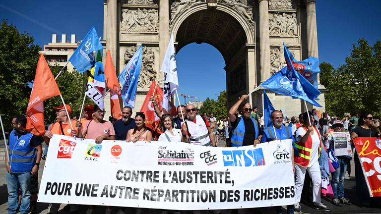 Demonstranten posieren am 18. September 2025 mit einem Transparent in Marseille im Südosten Frankreichs, während eines Tages landesweiter Streiks und Proteste, zu denen die Gewerkschaften wegen des französischen Staatshaushalts aufgerufen hatten.