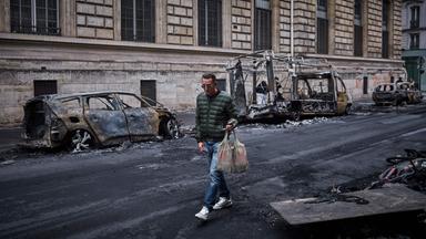 Frankreich, Paris: Ein Mann geht in der Rue Yves Toudic an einer Reihe ausgebrannter Fahrzeuge vorbei