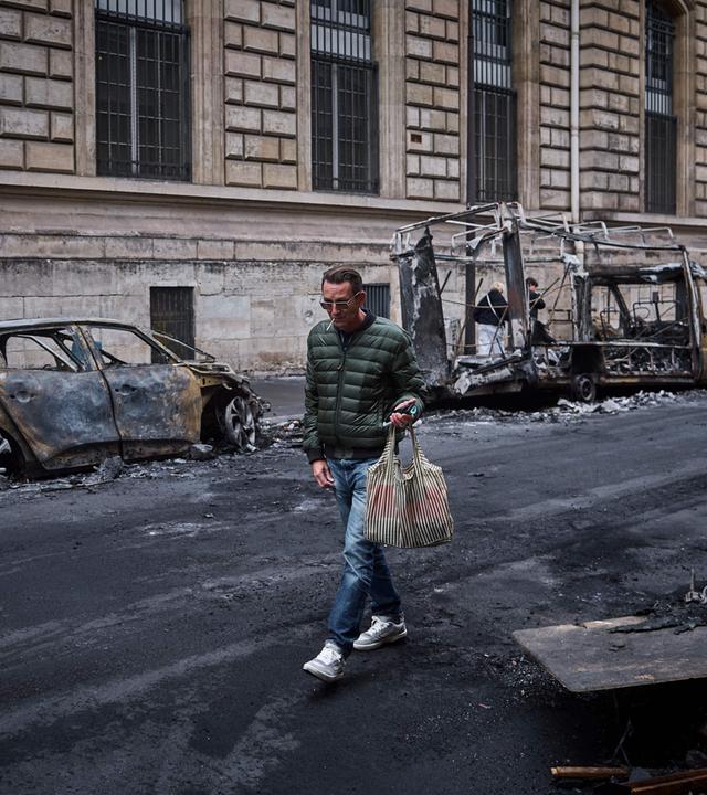 Frankreich, Paris: Ein Mann geht in der Rue Yves Toudic an einer Reihe ausgebrannter Fahrzeuge vorbei