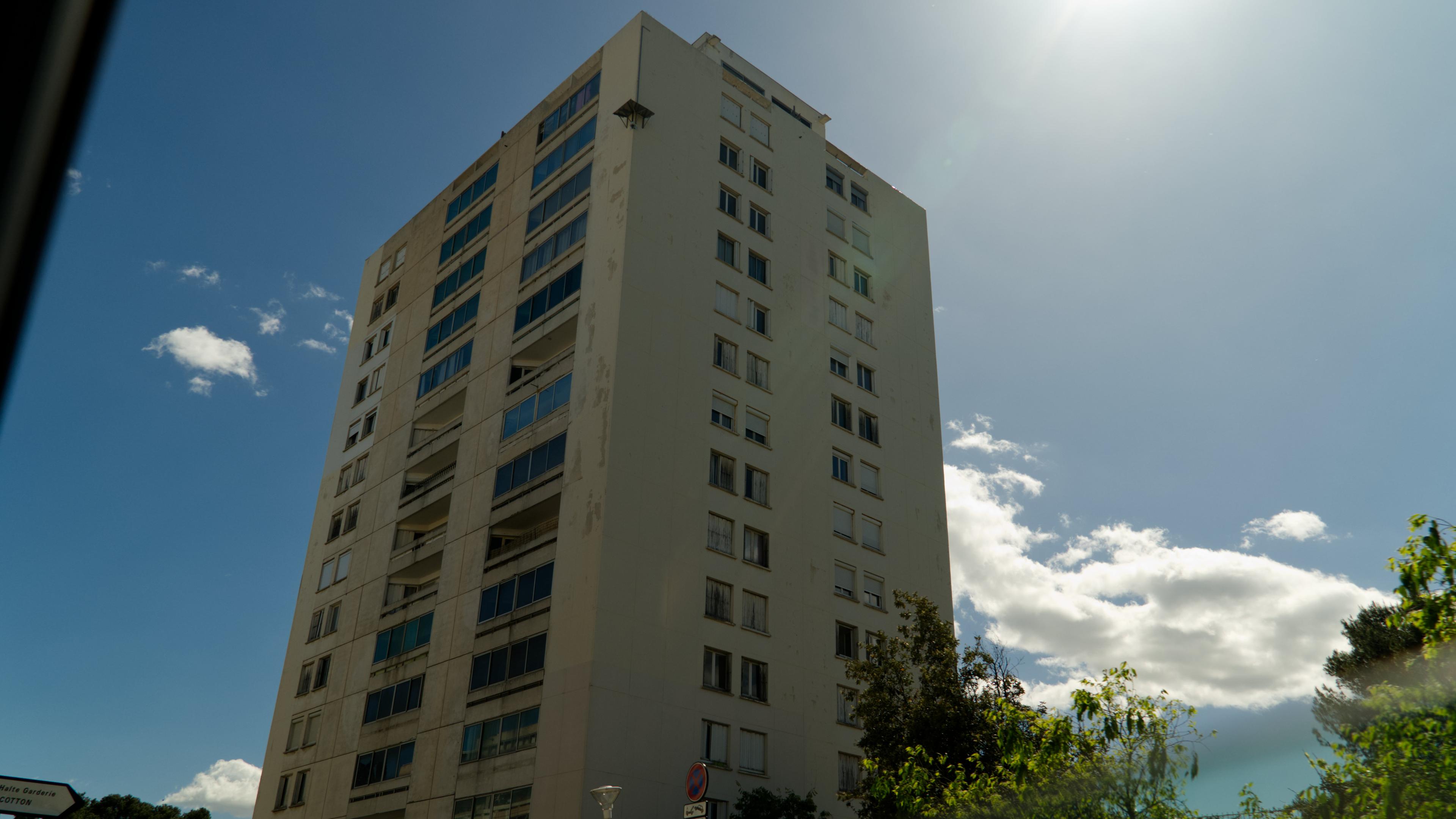 Ein Hochhaus mit über 14 Etagen vor blauem Himmel.