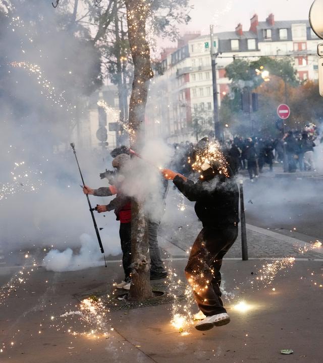 Ein Demonstrant zündet während Protesten in Pariseinen Feuerwerkskörper an.