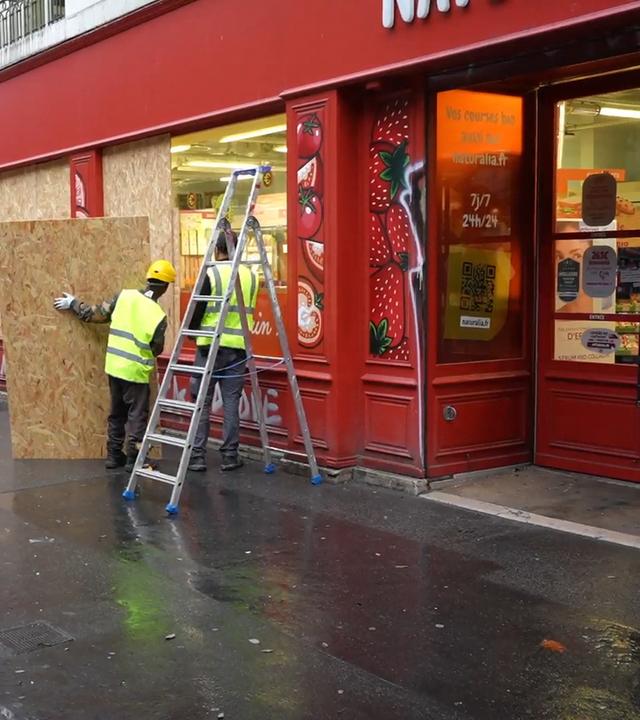 Die Eingänge und Fenster von Geschäften werden mit Holzplatten verbarrikadieren.