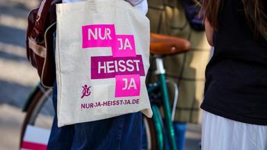 08.03.2025, Nordrhein-Westfalen, Köln: Bei einer Demo anlässlich des Internationalen Frauentages trägt eine Teilnehmerin eine Stofftasche mit der Aufschrift "Nur ja heisst ja".