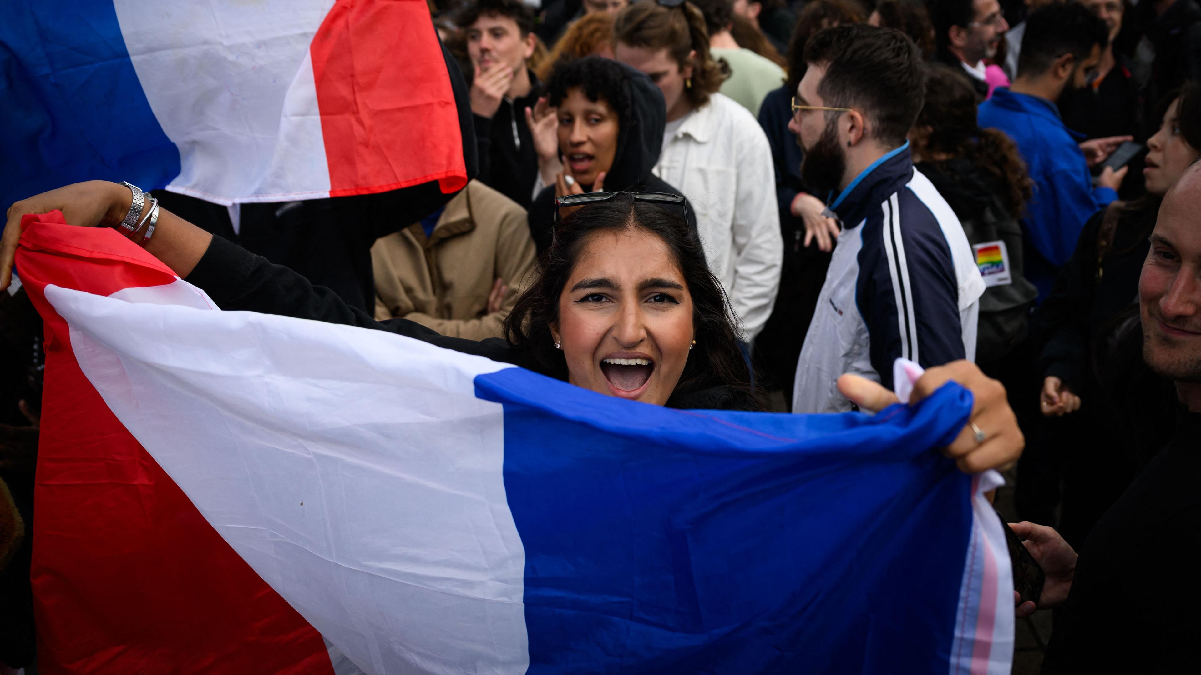 Eine Frau hält eine französische Nationalflagge bei einer Demonstration nachdem die ersten Ergebnisse der Parlamentswahlen veröffentlicht wurden. 