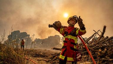 Ein Feuerwehrmann, der am Mittwoch, 6. August 2025, in der Nähe von Saint-Laurent-de-la-Cabrerisse, Südfrankreich, mit einem Schlauch gegen einen Waldbrand vorgeht.