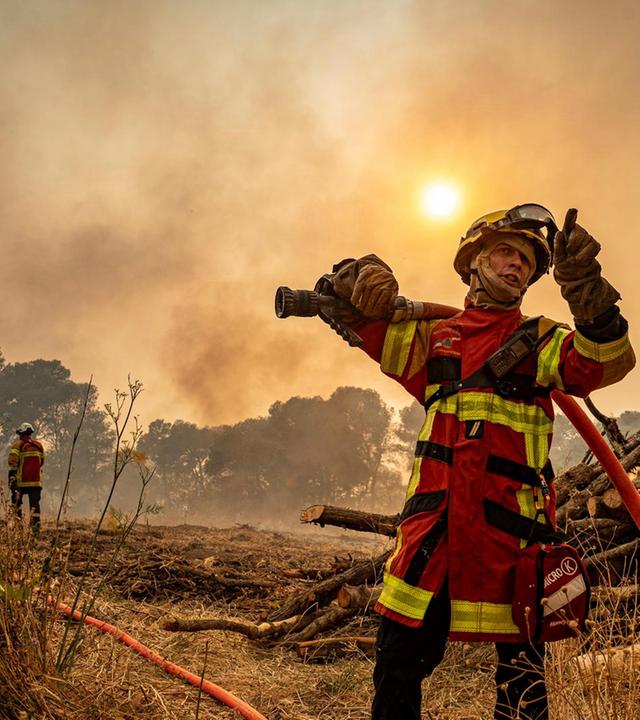 Ein Feuerwehrmann, der am Mittwoch, 6. August 2025, in der Nähe von Saint-Laurent-de-la-Cabrerisse, Südfrankreich, mit einem Schlauch gegen einen Waldbrand vorgeht.