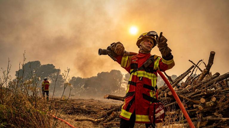 Ein Feuerwehrmann, der am Mittwoch, 6. August 2025, in der Nähe von Saint-Laurent-de-la-Cabrerisse, Südfrankreich, mit einem Schlauch gegen einen Waldbrand vorgeht.