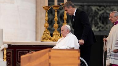 Papst Franziskus wird im Rollstuhl an dem Sarg des verstorbenen emeritierten Papstes Benedikt XVI. während öffentlichen Trauermesse für den emeritierten Papst Benedikt XVI. auf dem Petersplatz gefahren.