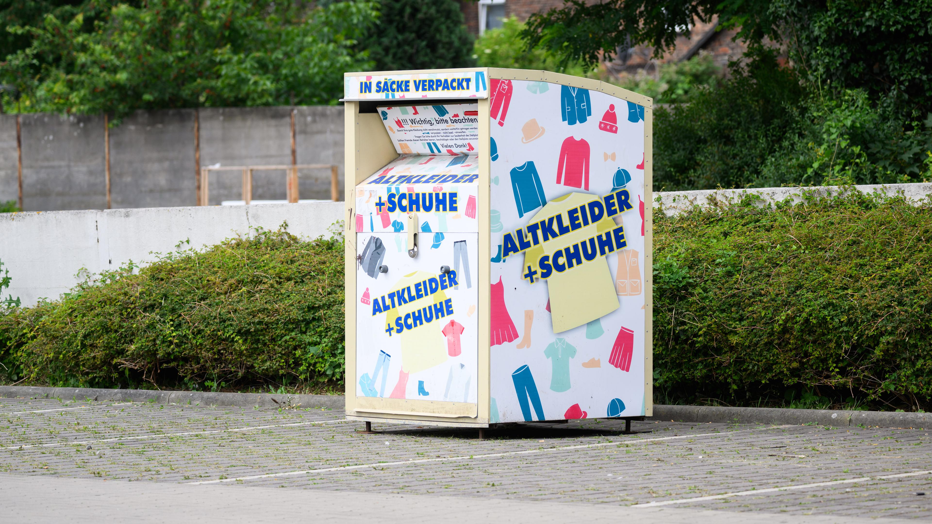 Ein Altkleidercontainer steht auf einem Supermarkt-Parkplatz.