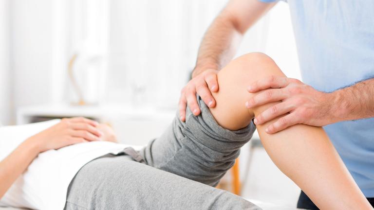 Frau wird am Knie behandelt