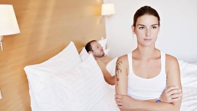 Frau sitzt lustlos am Bettrand