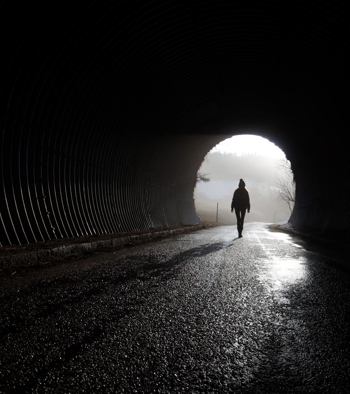 Eine Frau läuft durch eine dunkle Unterführung.
