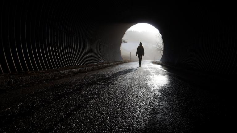 Eine Frau läuft durch eine dunkle Unterführung.