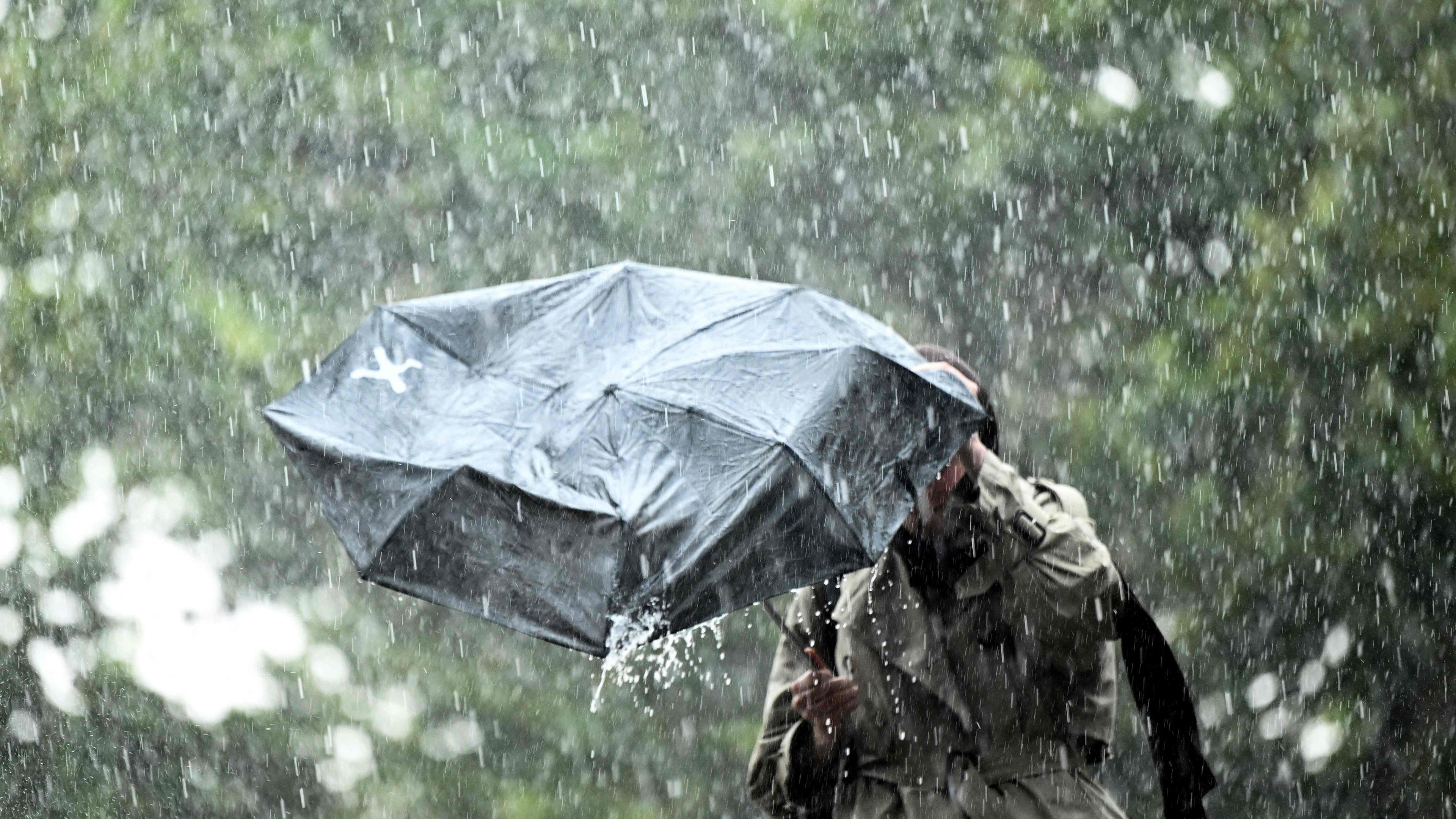 Frau mit Regenschirm im Starkregen