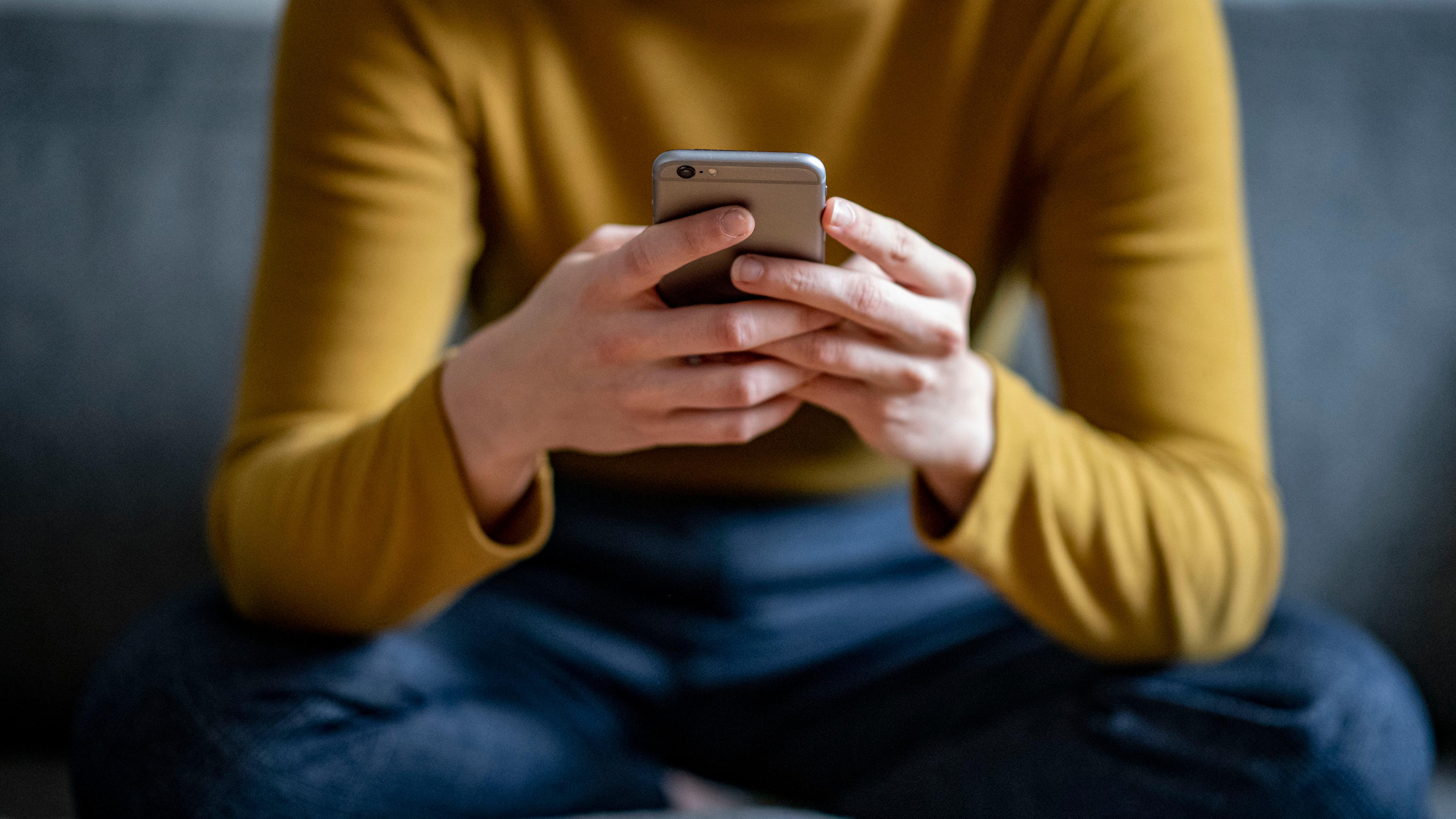 Berlin: Eine junge Frau hält ein Smartphone in der Hand.