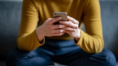 Berlin: Eine junge Frau hält ein Smartphone in der Hand.