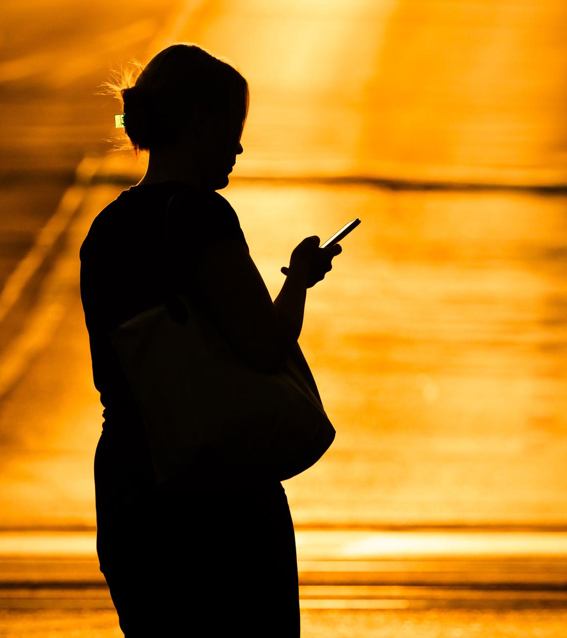 Symbolbild: Eine Frau läuft mit einem Smartphone in der Hand über eine Straße